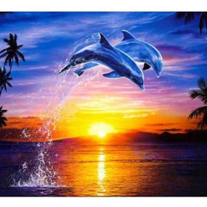 Diamond painting of two dolphins leaping out of the ocean at a colorful sunset. 