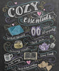 Diamond painting of a chalkboard with the words "Cozy Essentials" surrounded by cozy-themed images, such as a blanket, slippers, hot tea, and a book.