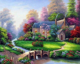 Diamond painting of a cozy house with a red roof on the bank of a river with a stone bridge.