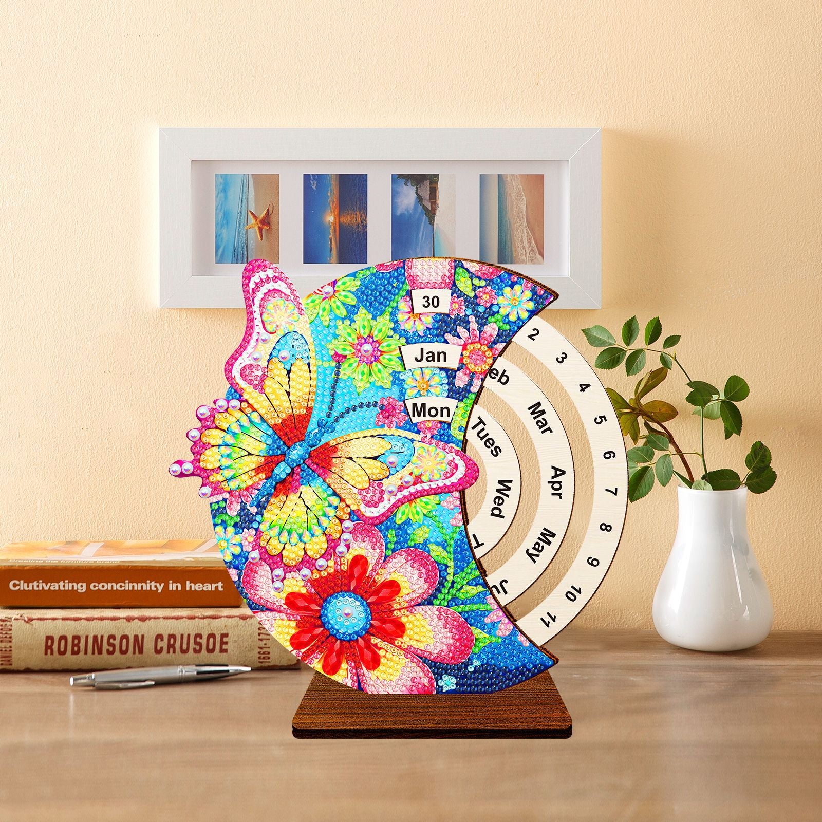 Rotating diamond painting calendar featuring a butterfly design, used as home decor on a desk with books, with month and day indicators, DIY craft