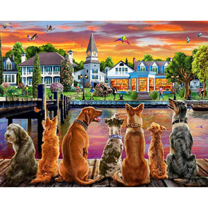 Diamond painting of a group of dogs sitting on a dock, watching the sunset over a seaside town