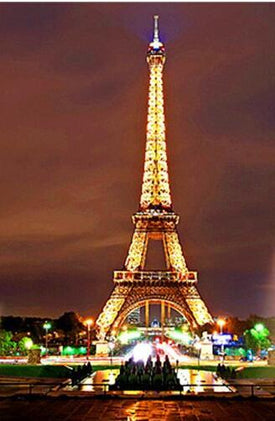 Diamond painting of the Eiffel Tower illuminated at night, with the city lights in the background
