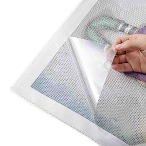 Hand revealing the sticky surface of a diamond painting canvas by peeling back the protective film, preparing for the placement of diamond resins
