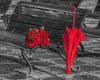 Diamond painting of a red and black rose bouquet with an umbrella leaning against a wooden chair.