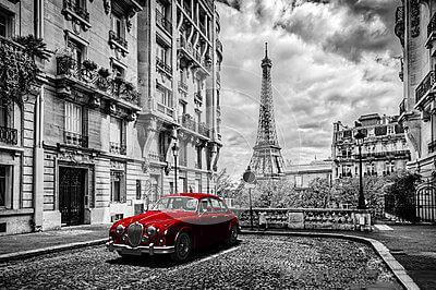 Image of Red classic car parked in Paris street with Eiffel Tower in background.