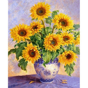 Vibrant diamond painting of a bouquet of sunflowers in a blue and white porcelain vase, with a soft pastel background.